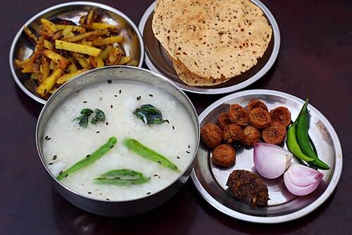 A bowl of pakhala with fried fish and sides